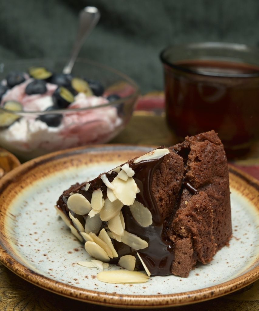 A tea-time. Chocolate cake, a yogurt with strawberry jam and blueberries
